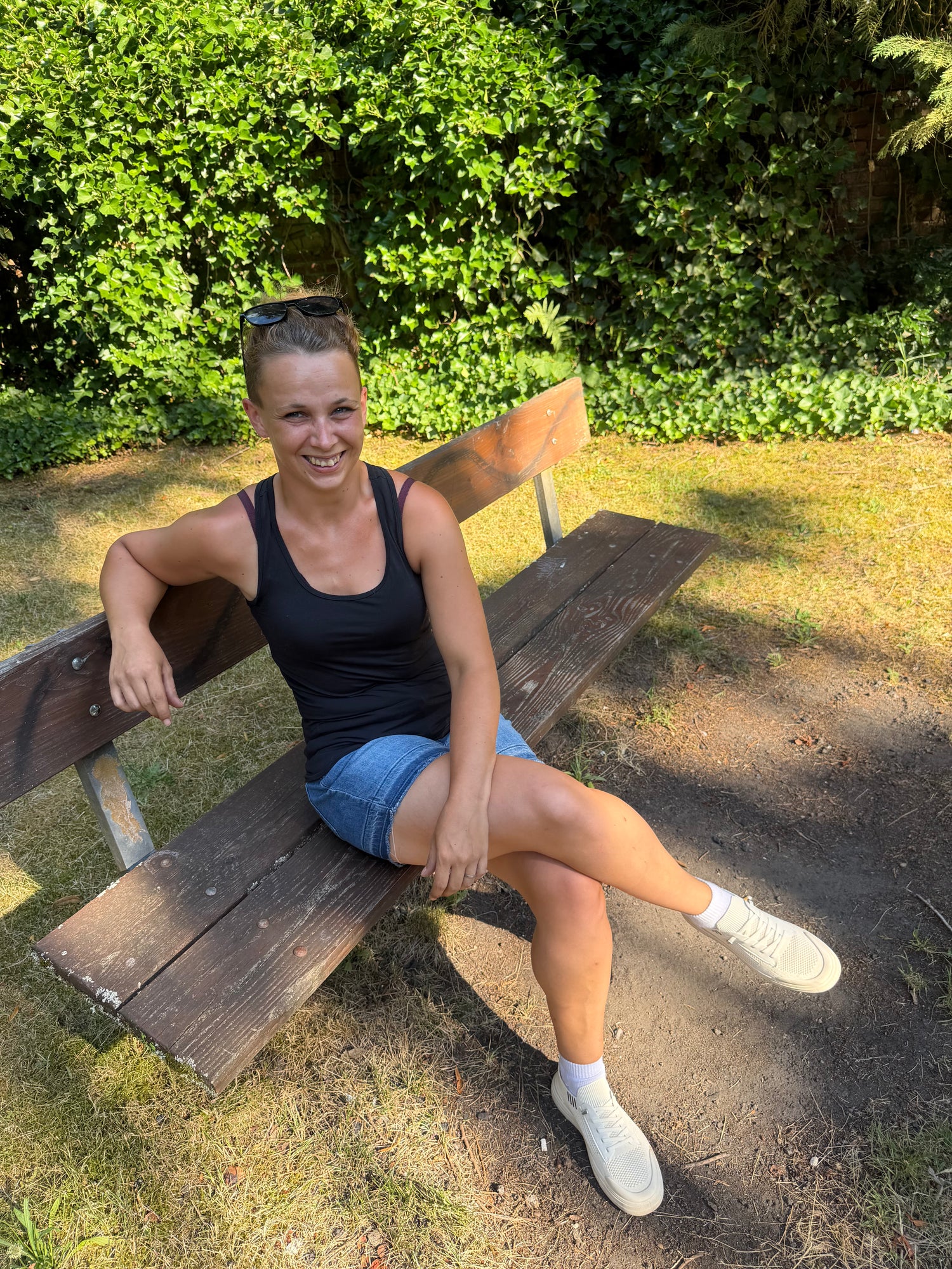 Anja Schöneberger sitzt lächelnd auf einer Holzbank im Grünen